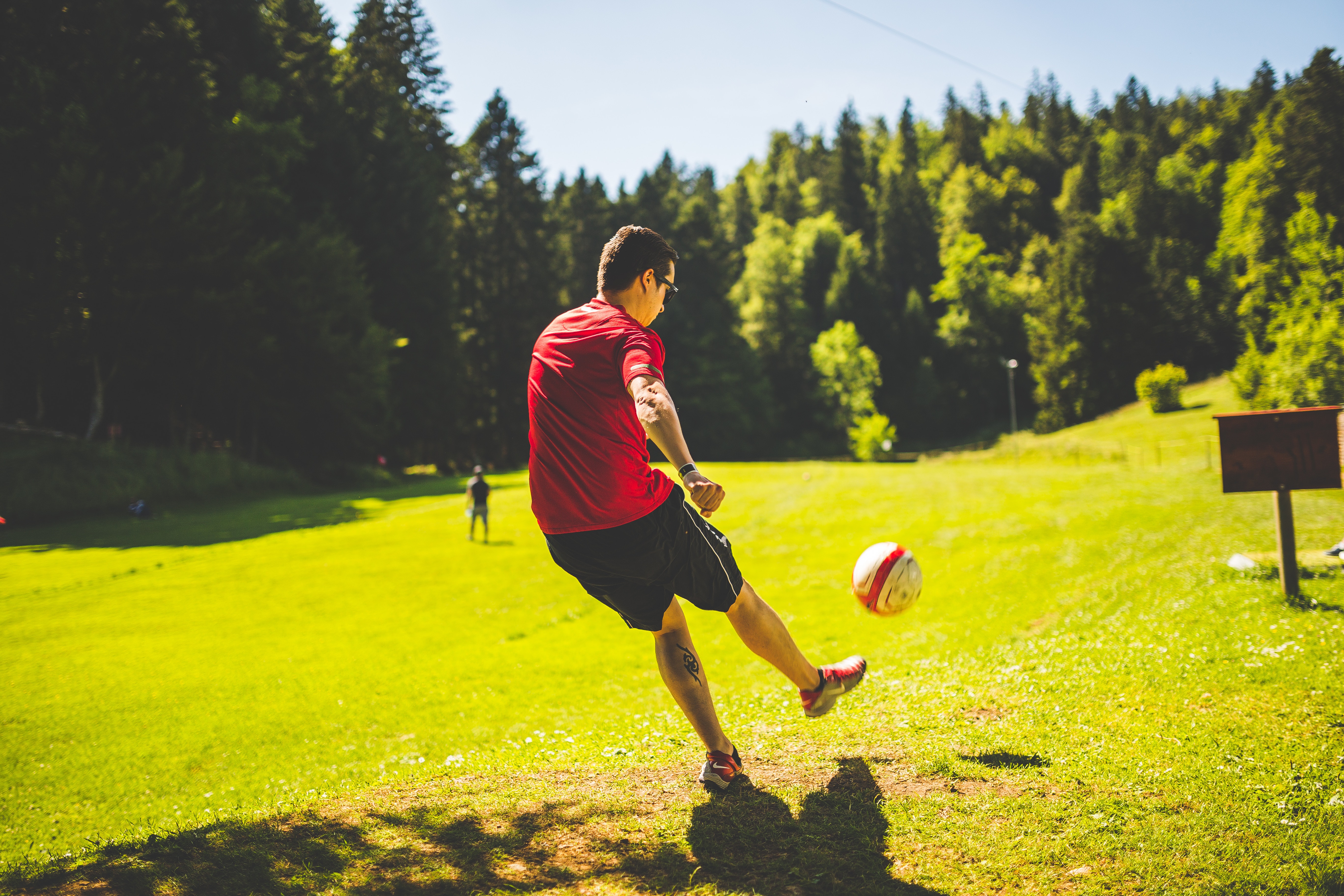Люди на футбольном поле. Парень с мячом. Футбол на природе. Парень с футбольным мячом. Увлечение спортом.